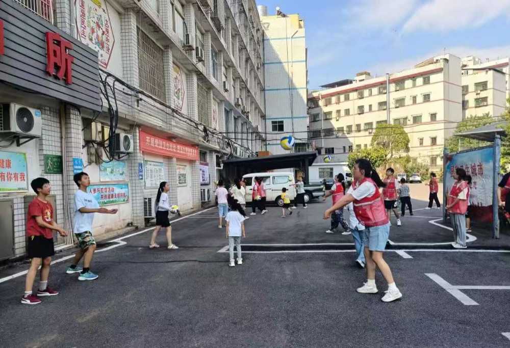 图为志愿者与小朋友一起打气排球