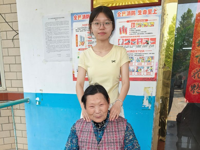 图为实践团成员刘飞彤在老年公寓为老人捏肩膀