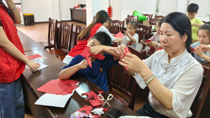 图为居民与小朋友共同参与民族剪纸手工制作