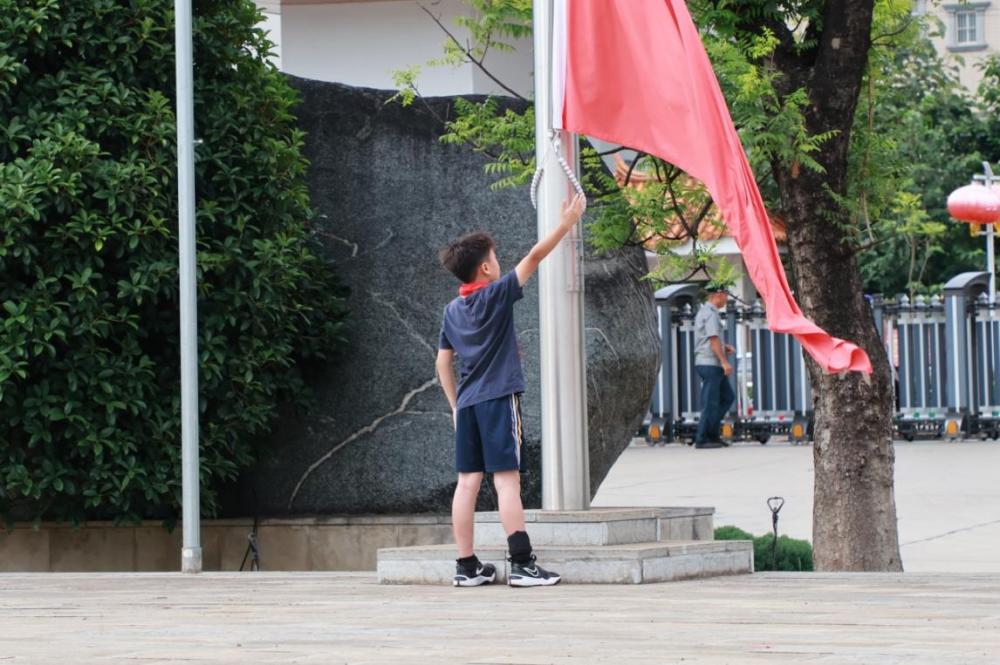 图为志愿者与全体师生同升国旗,纪念聂耳 李晓童摄